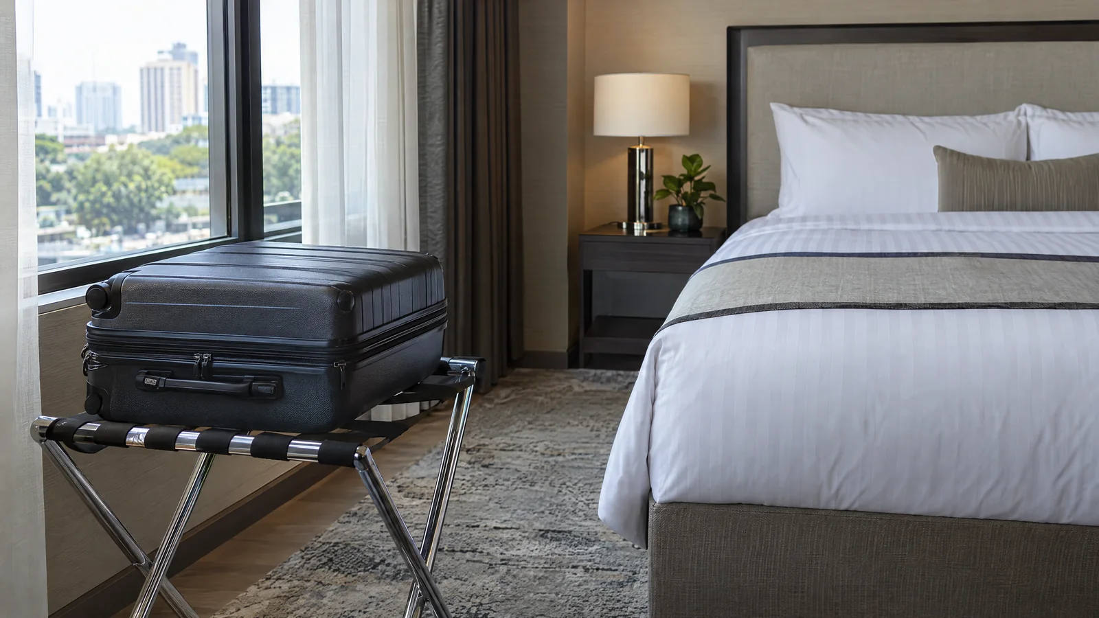 Suitcase on a metal luggage rack away from the bed in a hotel room